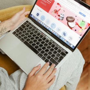 A woman sits comfortably indoors, browsing an online shopping website on her laptop.